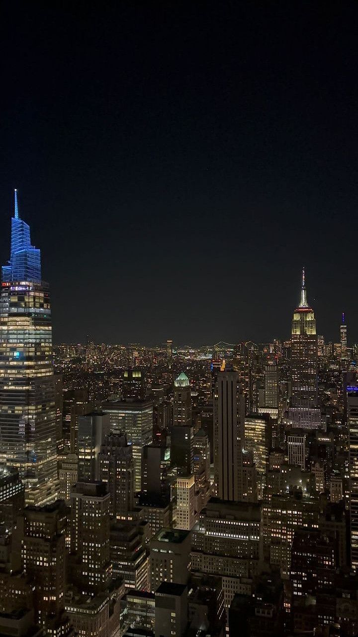 an aerial view of the city at night with skyscrapers lit up in blue and white