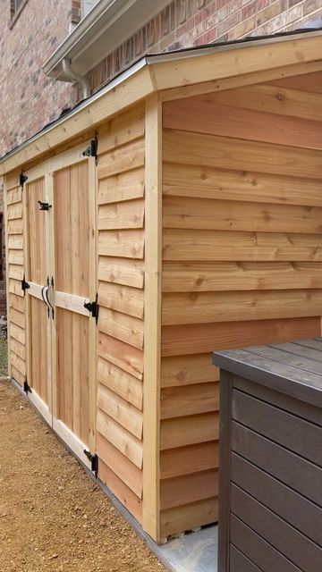 a woman standing next to a wooden shed on the side of a building with its door open