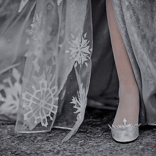 a woman's feet wearing silver shoes with snowflakes on them and sheer fabric