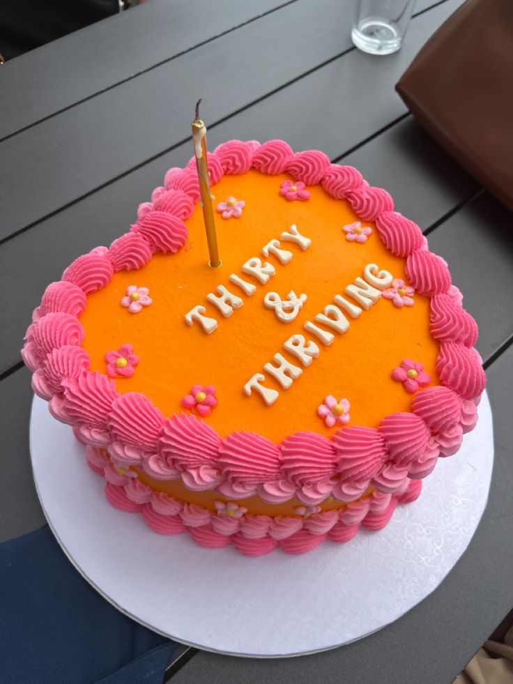 a pink and orange birthday cake on a table