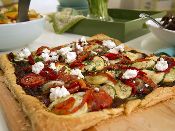 a pizza with tomatoes, cucumbers and feta cheese on it sitting on a cutting board