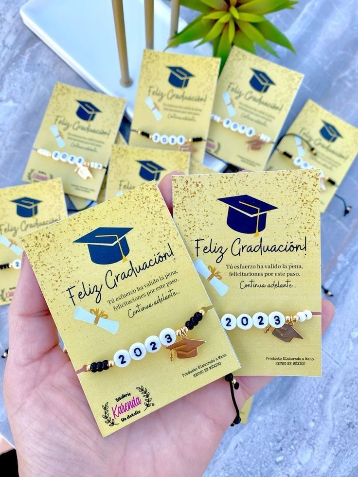 four graduation bracelets are being held in front of a plant