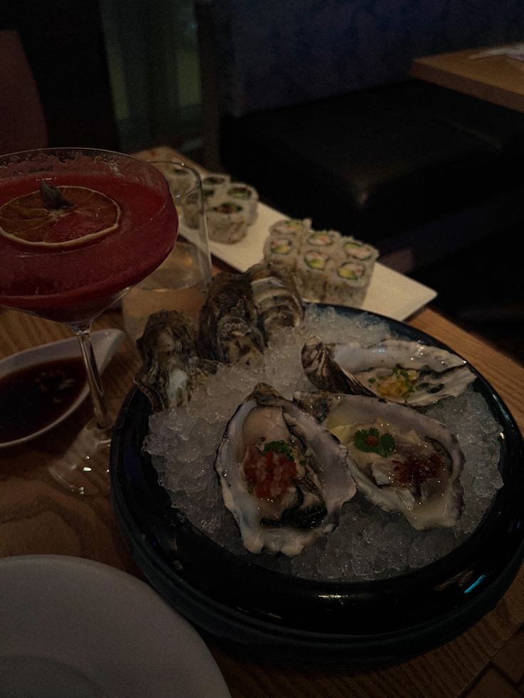 oysters on the half shell in an ice tray with wine glasses and plates behind it