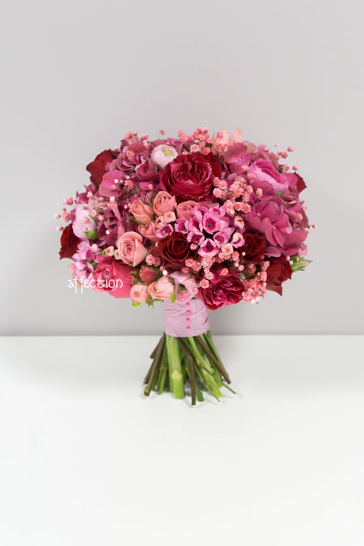 a bouquet of pink and red flowers sitting on top of a table