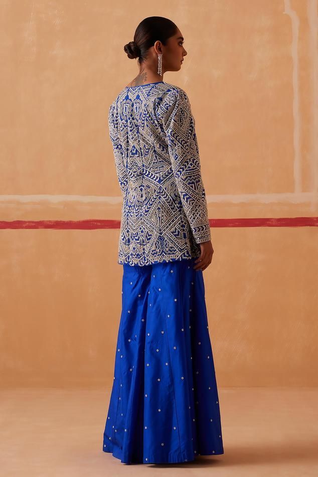 Ink blue full sleeve jacket with silver zari, thread, sequin, bead, cutdana embroidery in geometric pattern. Paired with gharara.
Components: 2
Pattern: Embroidery
Type Of Work: Zari, thread, sequin, bead, cutdana
Neckline: Leaf neck
Sleeve Type: Full sleeves
Fabric: Jacket: Organza, Gharara: Pure Silk
Color: Blue
Other Details: 
Length:
Jacket: 30 inches
Gharara: 42-43 inches
Occasion: Sangeet - Aza Fashions Organza Gharara, Sureena Chowdhri, Cutdana Embroidery, Organza Embroidery, Ink Blue, Pattern Embroidery, Embroidered Jacket, Sleeve Jacket, Full Sleeves