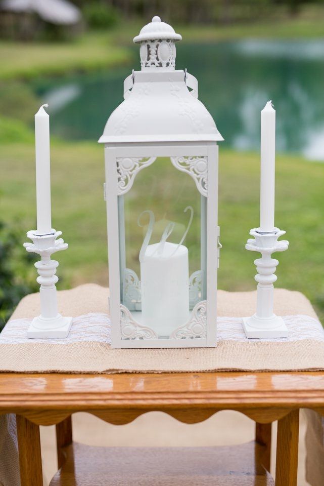 a white lantern sitting on top of a wooden table next to a small candle holder