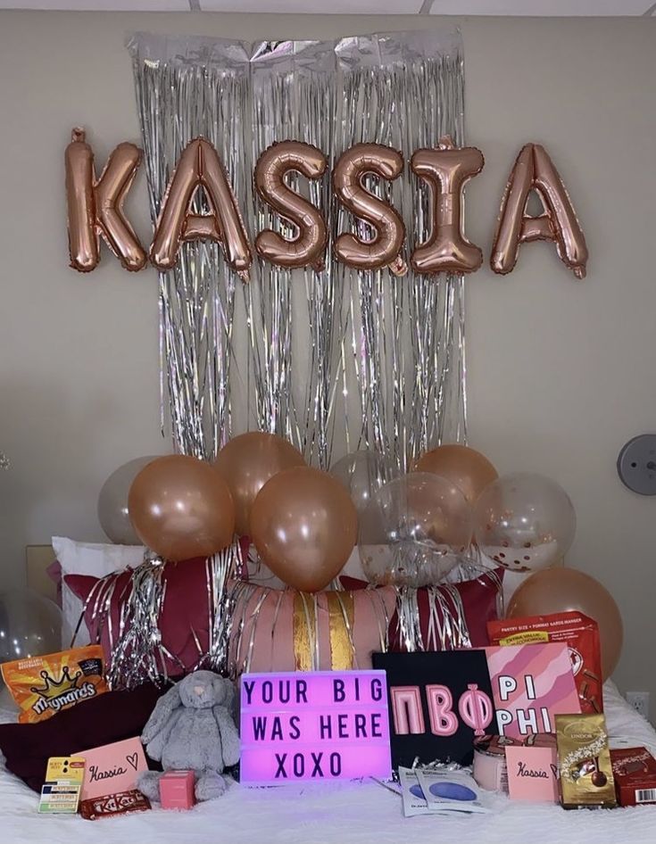 a bed topped with lots of balloons next to a sign that says kassia