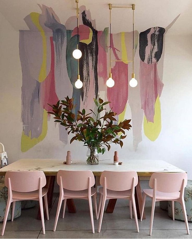 a dining room table with pink chairs and an abstract painting on the wall behind it