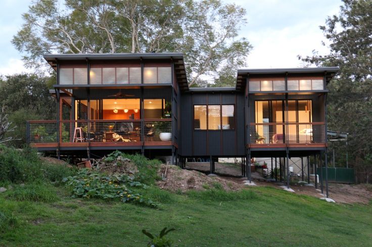 two houses on the side of a hill with trees in the background