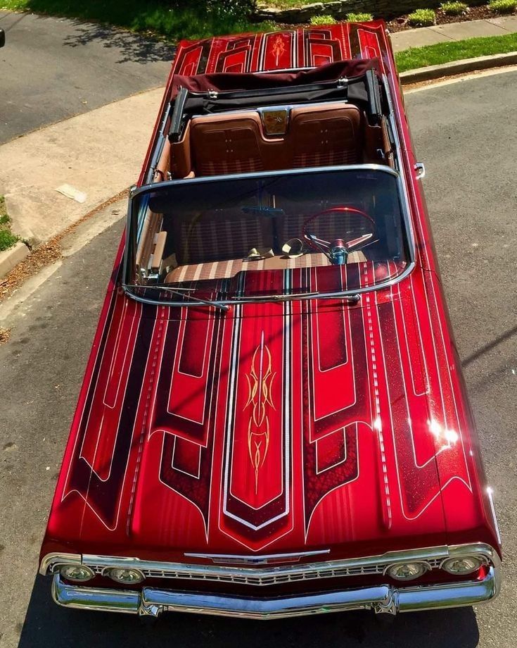 an old red car parked on the side of the road