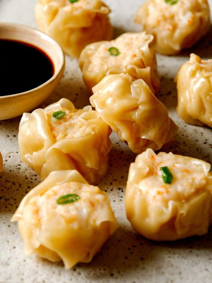 some dumplings are sitting on a plate with dipping sauce