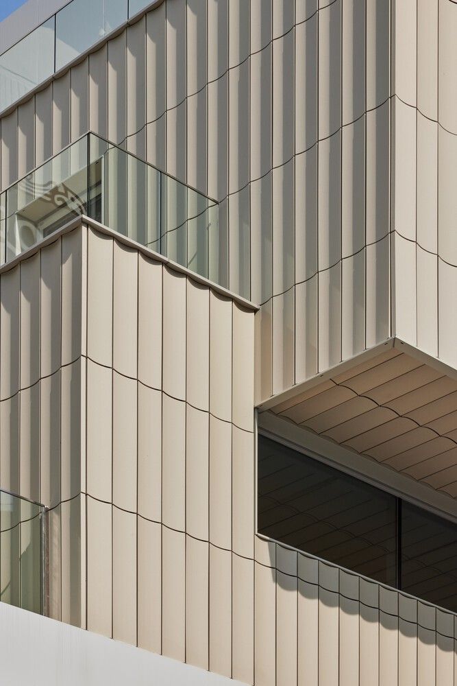 an airplane is flying in front of a building with glass balconies on the windows