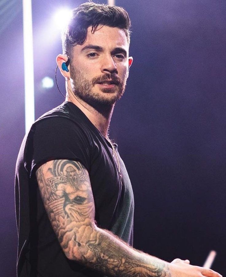 a man with tattoos on his arm holding a microphone