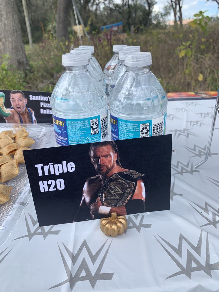 a table topped with bottles of water and cookies next to a sign that says triple h2o