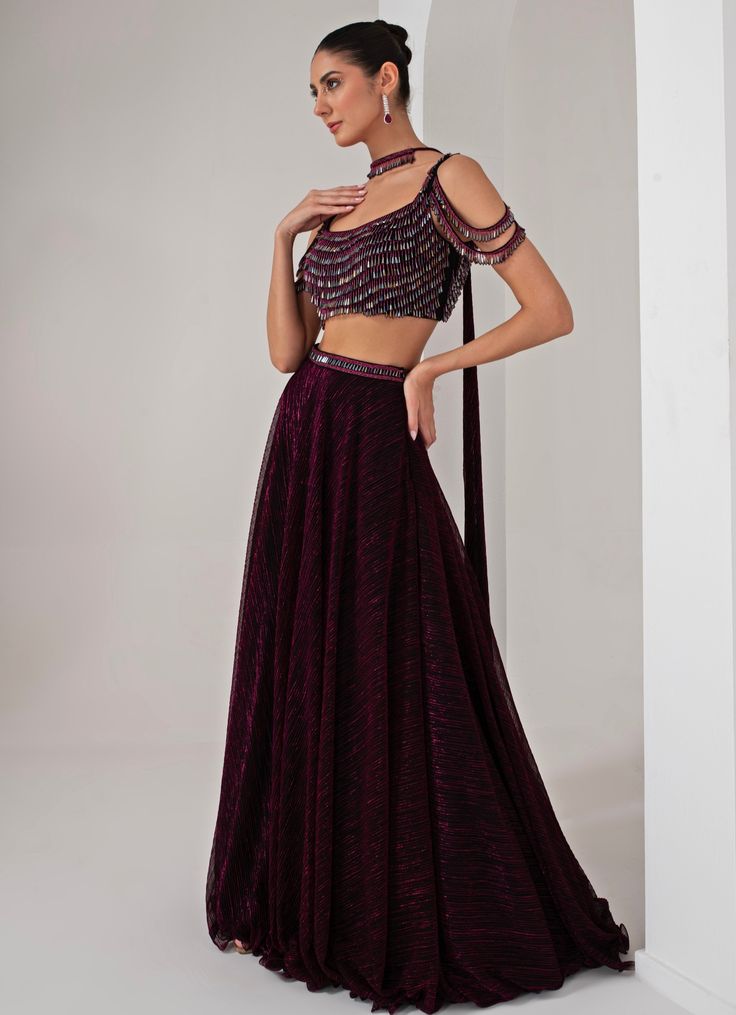 This stunning Black Platinoir Crepe Embellished Lehenga Set exudes modern elegance and glamour. Crafted from luxurious platinoir crepe, the black lehenga features a dramatic full-length skirt with all-over metallic brazen fall detailing, adding a shimmering effect with every movement. The crystal-embroidered waistband accentuates the waist, offering a refined silhouette. Teamed with a cold shoulder blouse, the ensemble reaches new heights with its halo crystal tassel embellishments, delivering a unique and stylish twist. The look is completed with a choker-style embellished dupatta, perfectly complementing the outfit with a sophisticated touch. Ideal for Cocktail parties, Sangeet nights, or evening events, this lehenga set is designed for those who wish to make a bold and fashionable state Festive Floor-length Embellished Skirt, Embellished Floor-length Festive Skirt, Elegant Evening Georgette Skirt, Fitted Georgette Evening Skirt, Evening Fitted Georgette Skirt, Elegant Embellished Georgette Skirt, Festive Floor-length Pre-draped Saree For Gala, Festive Evening Lehenga, Party Wear Pre-draped Floor-length Saree For Gala