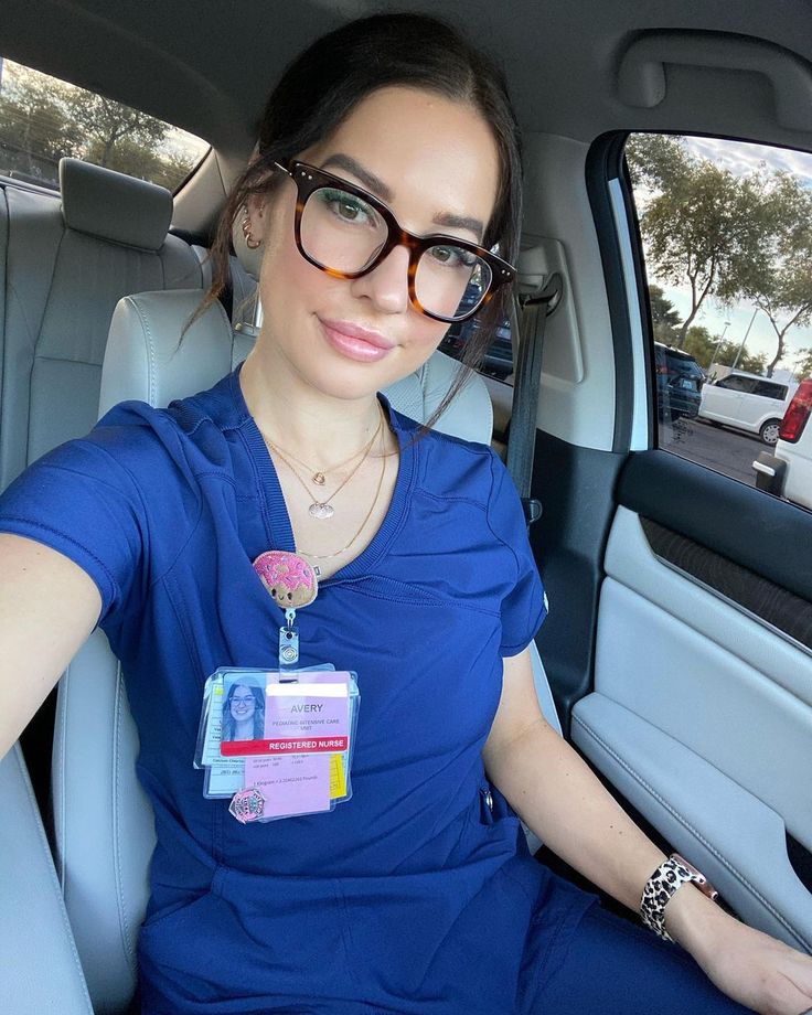 a woman sitting in the back seat of a car wearing glasses and a blue shirt