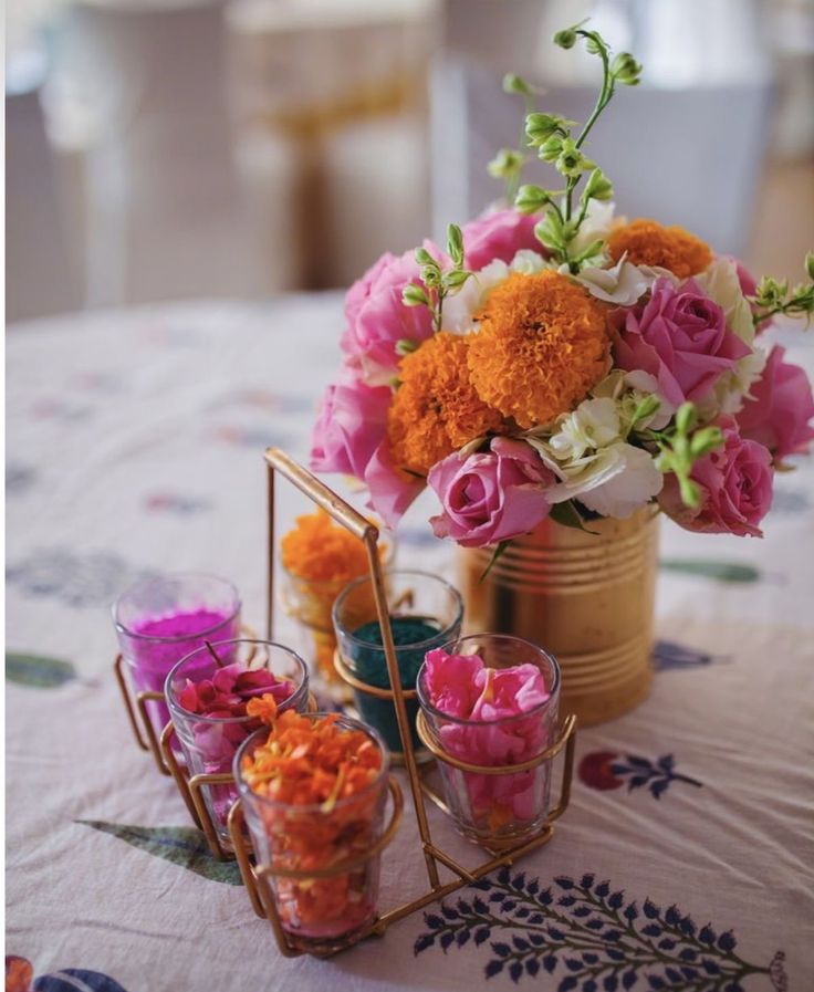 a table topped with vases filled with flowers next to candles and tea cups on top of a table