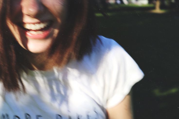 a woman with long brown hair smiling at the camera while wearing a white t - shirt