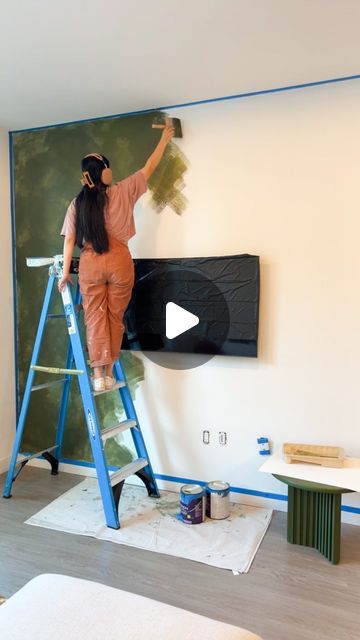 a woman in an orange jumpsuit painting a wall