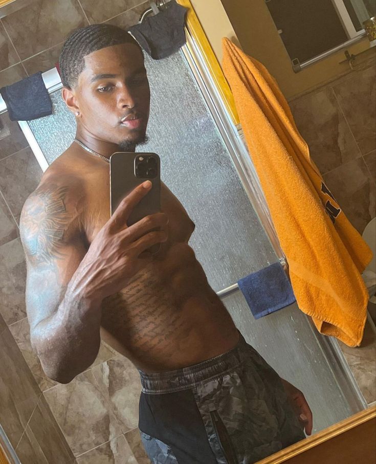 a shirtless man taking a selfie in front of a mirror with his cell phone