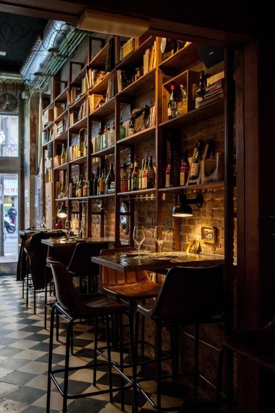 an empty restaurant with lots of bottles and glasses on the shelves in front of it