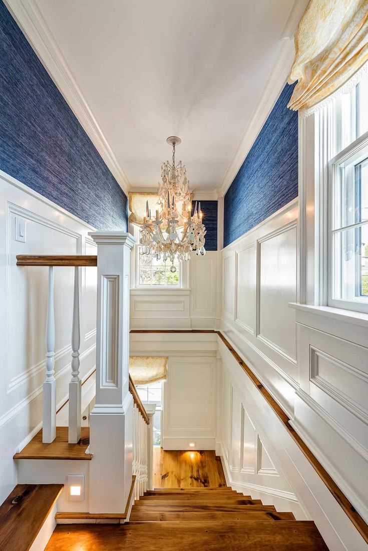 an empty staircase with chandelier and blue walls