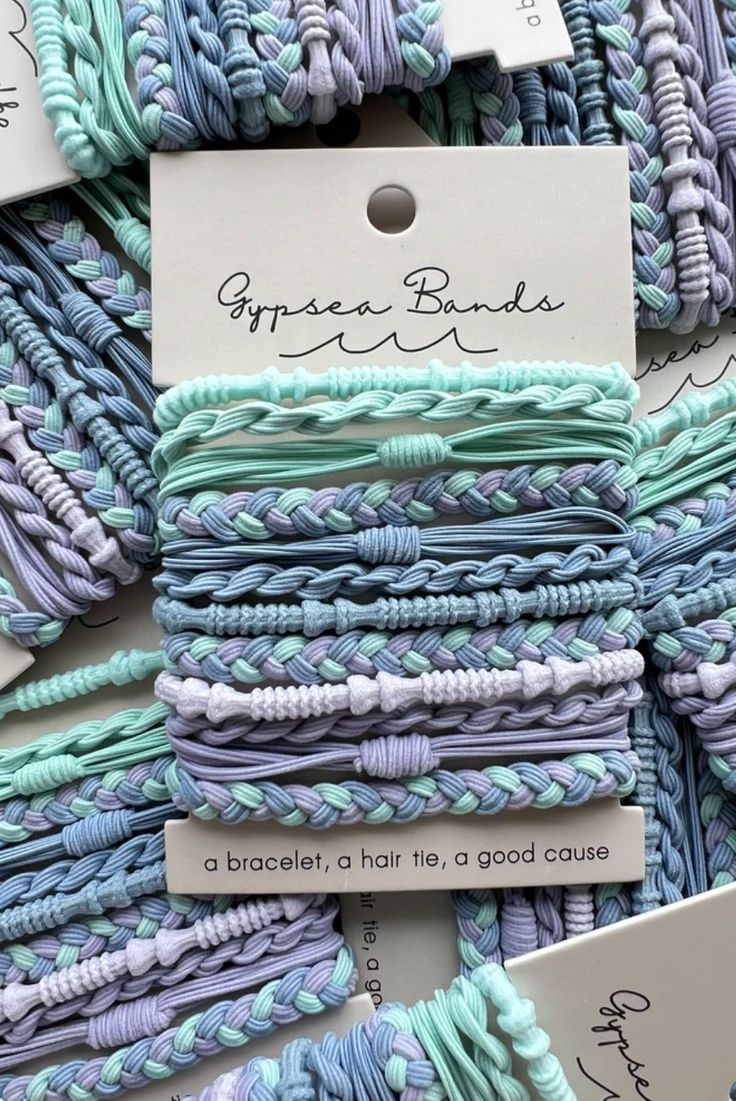 blue and purple braided hair ties are stacked on top of each other with white tags attached to them