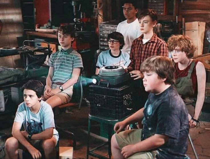 a group of young boys sitting next to each other in front of a pile of junk