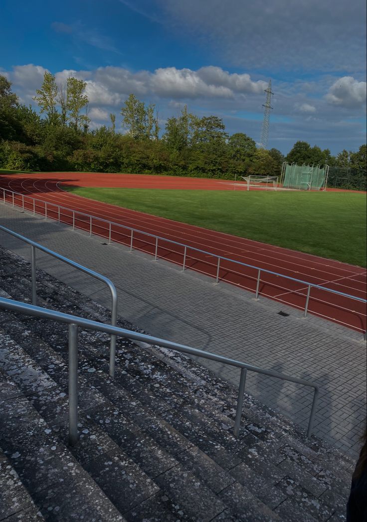 an empty stadium with stairs leading up to the bleachers and grass field in the background