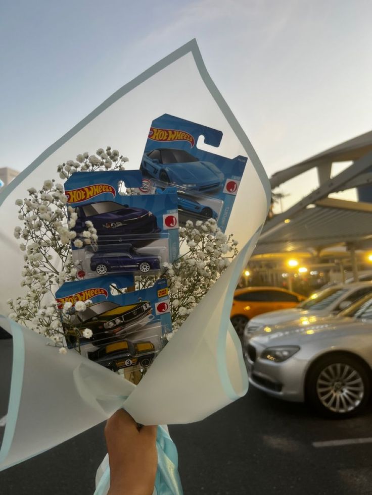 a person holding a bouquet of flowers in front of a parking lot filled with cars