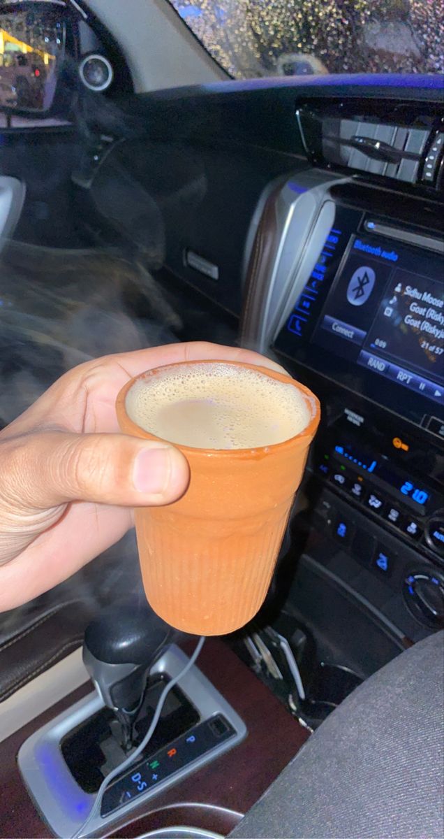 a person is holding a cup in their hand while sitting in the passenger seat of a car