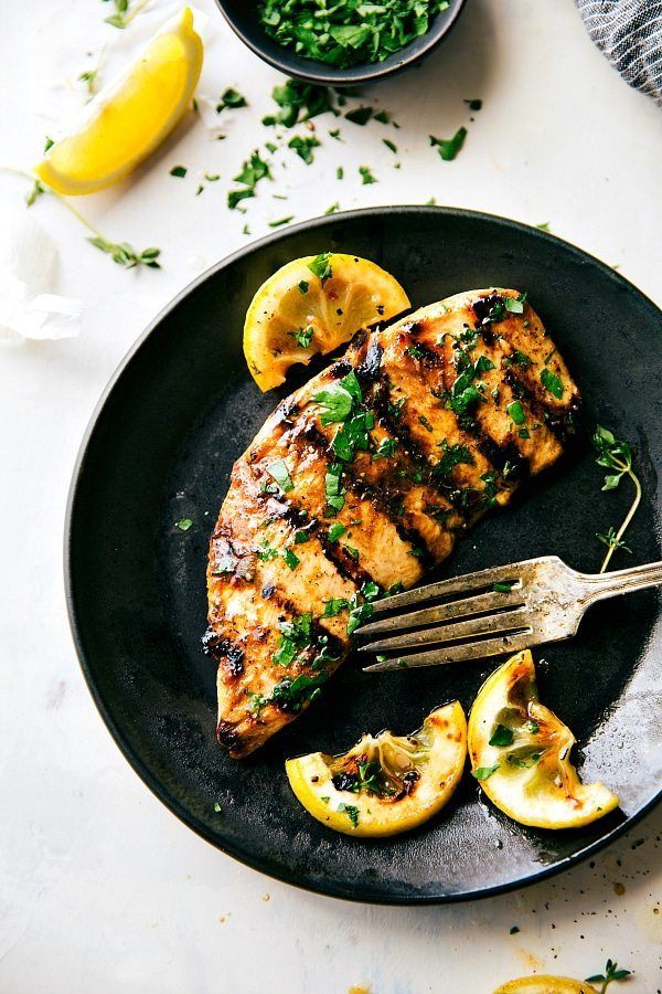 grilled chicken with lemons and parsley on a black plate