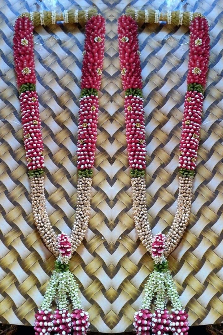 two red and white beaded necklaces are hanging on a wall next to each other