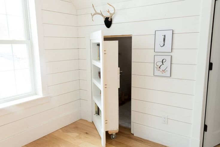 an empty room with white walls and wood flooring is pictured in this image, there is a cabinet next to the door