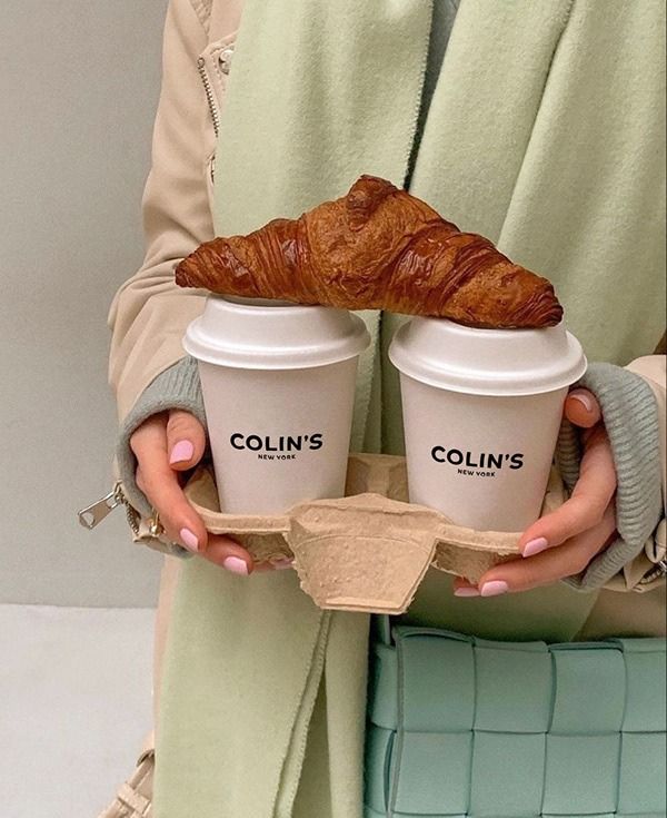 the woman is holding two cups with croissants on them and one has a baguette in it