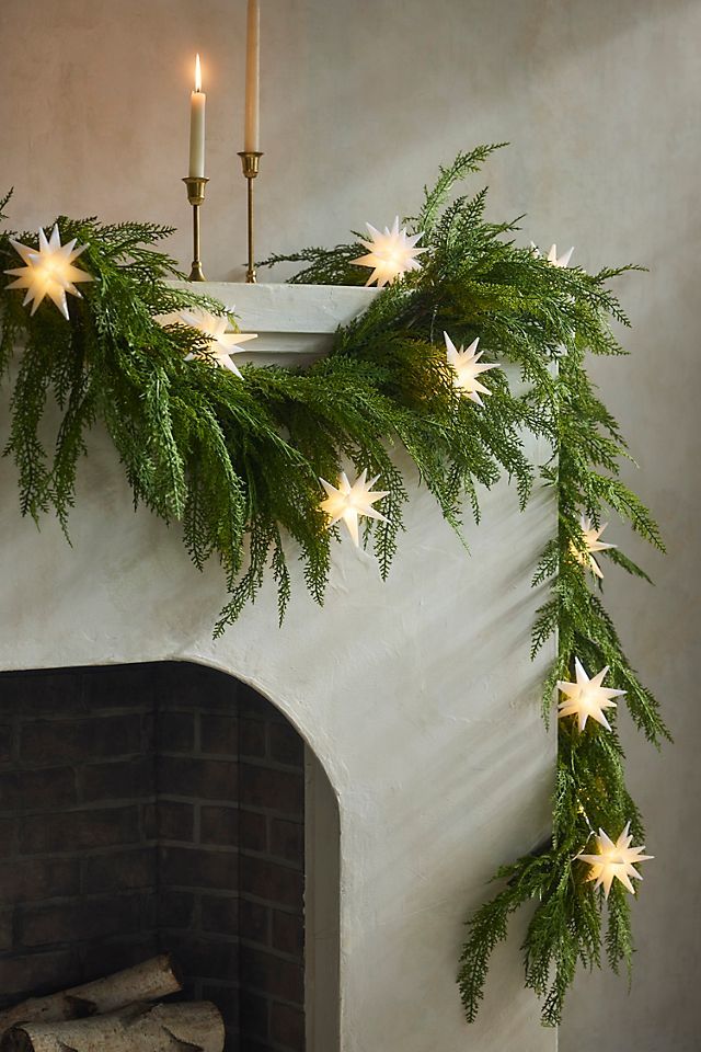 a christmas garland with white stars hanging from it's side next to a fireplace