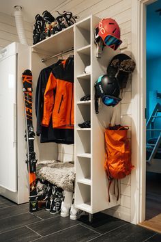 a snowboard and ski equipment are on shelves in the closet next to an open door