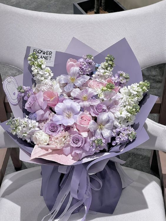 a bouquet of flowers sitting on top of a white chair with a purple ribbon around it