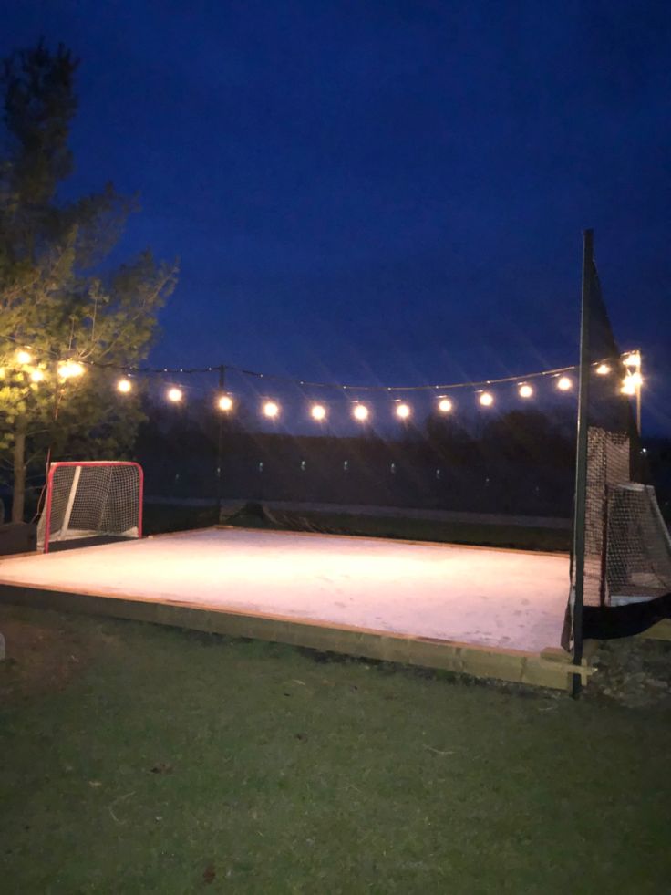 an outdoor ice rink with lights strung over it