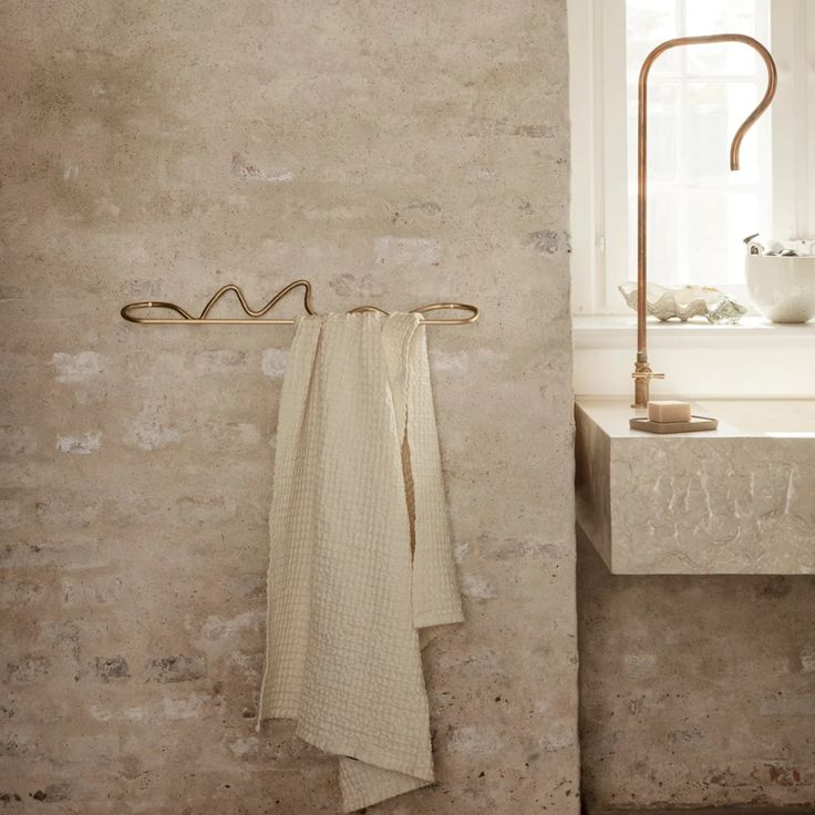 a towel hanging on a rack next to a sink in a room with stone walls