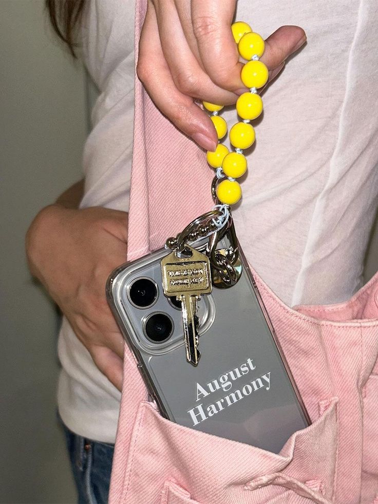 a person holding a cell phone with a keychain attached to the back of it