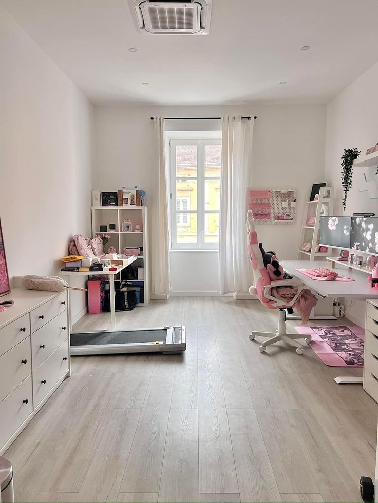 a room with lots of white furniture and pink accessories on the floor, along with a large window