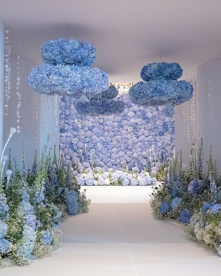 a white and blue floral display in the middle of a room with lots of flowers