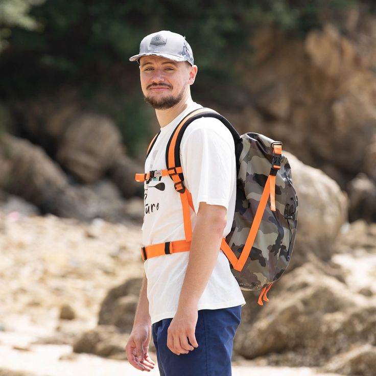 a man with a backpack is walking on the beach and smiling at the camera,