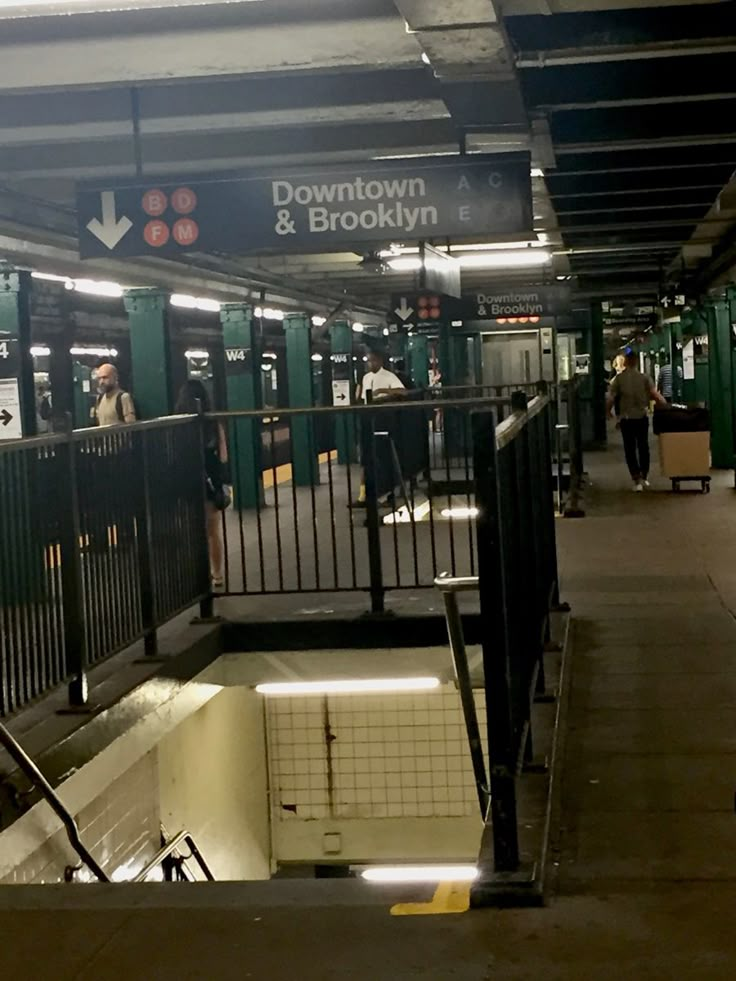 a subway station with people waiting for their trains to arrive and leave the station at night