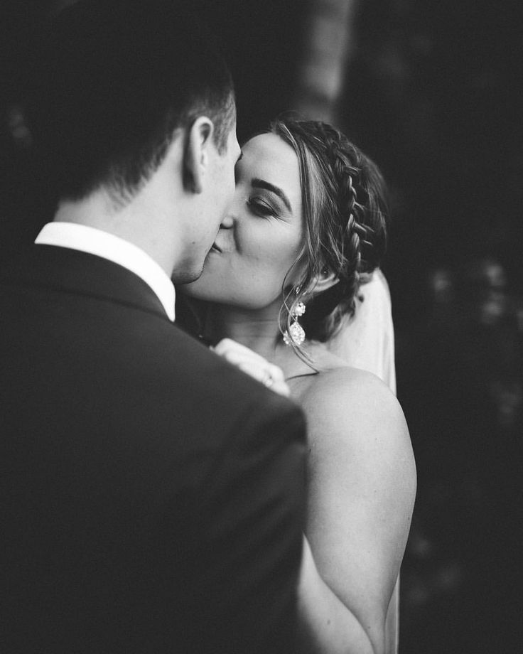 a bride and groom sharing a kiss at the end of their wedding day in black and white