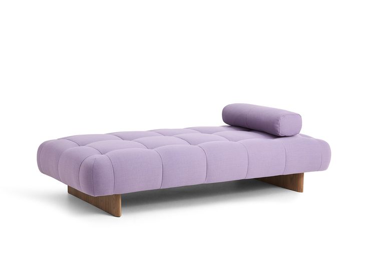 a purple couch sitting on top of a white floor next to a wooden legrest