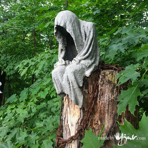 a statue sitting on top of a tree stump in the woods