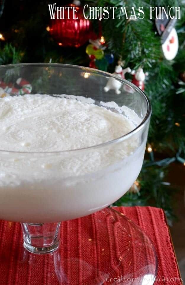 white christmas punch in a glass bowl on a red place mat next to a christmas tree