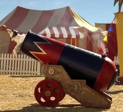 an old fashioned cannon on wheels in front of a circus tent